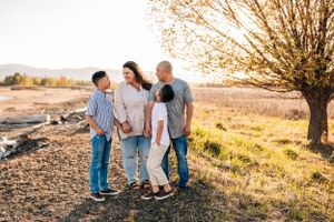 Group portrait of a family standing together outdoors under an autumn tree.