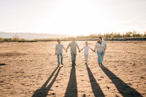 Silhouettes of a family walking together on a beach during sunset.