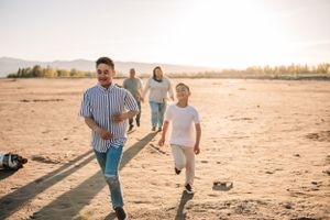 People running and playing together on a sandy beach at sunset.
