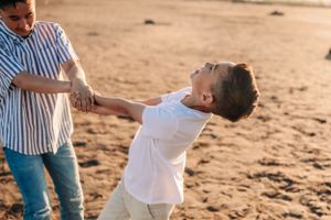 Playful moment captured between two people spinning and dancing on sandy ground.