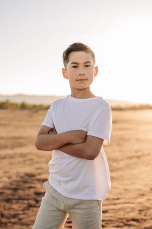 Young person in white t-shirt standing confidently against desert backdrop.