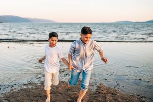 Two people running and playing together on a beach at sunset.