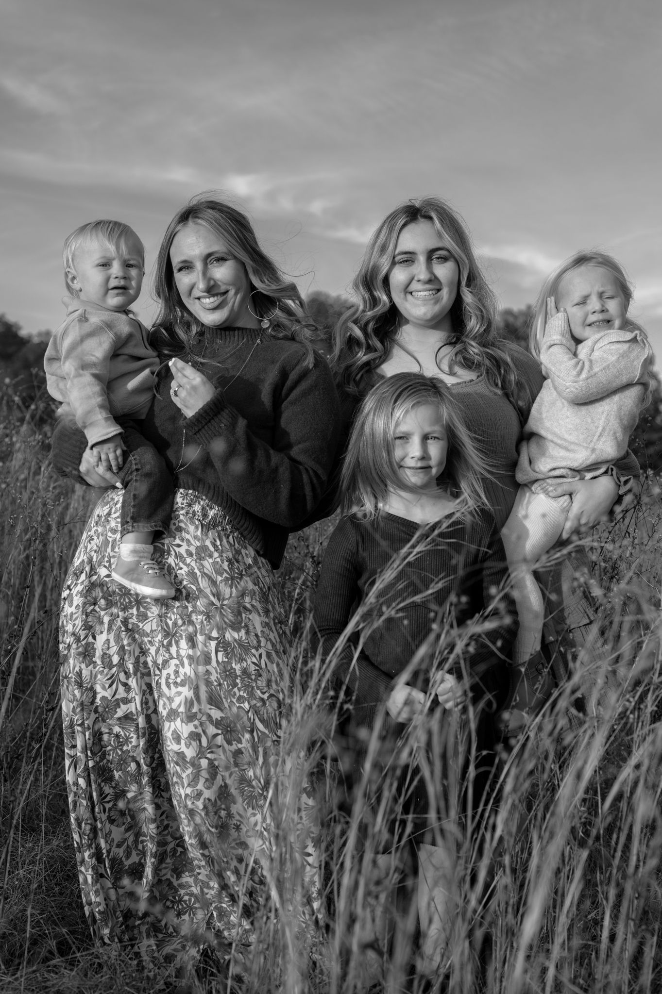 Black and white group portraits captured in tall grass with natural expressions.
