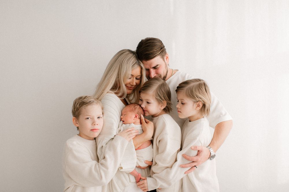 Newbornkuvaus koko perheen kesken, koko perhe mukana valokuvassa vauvan ympärillä.