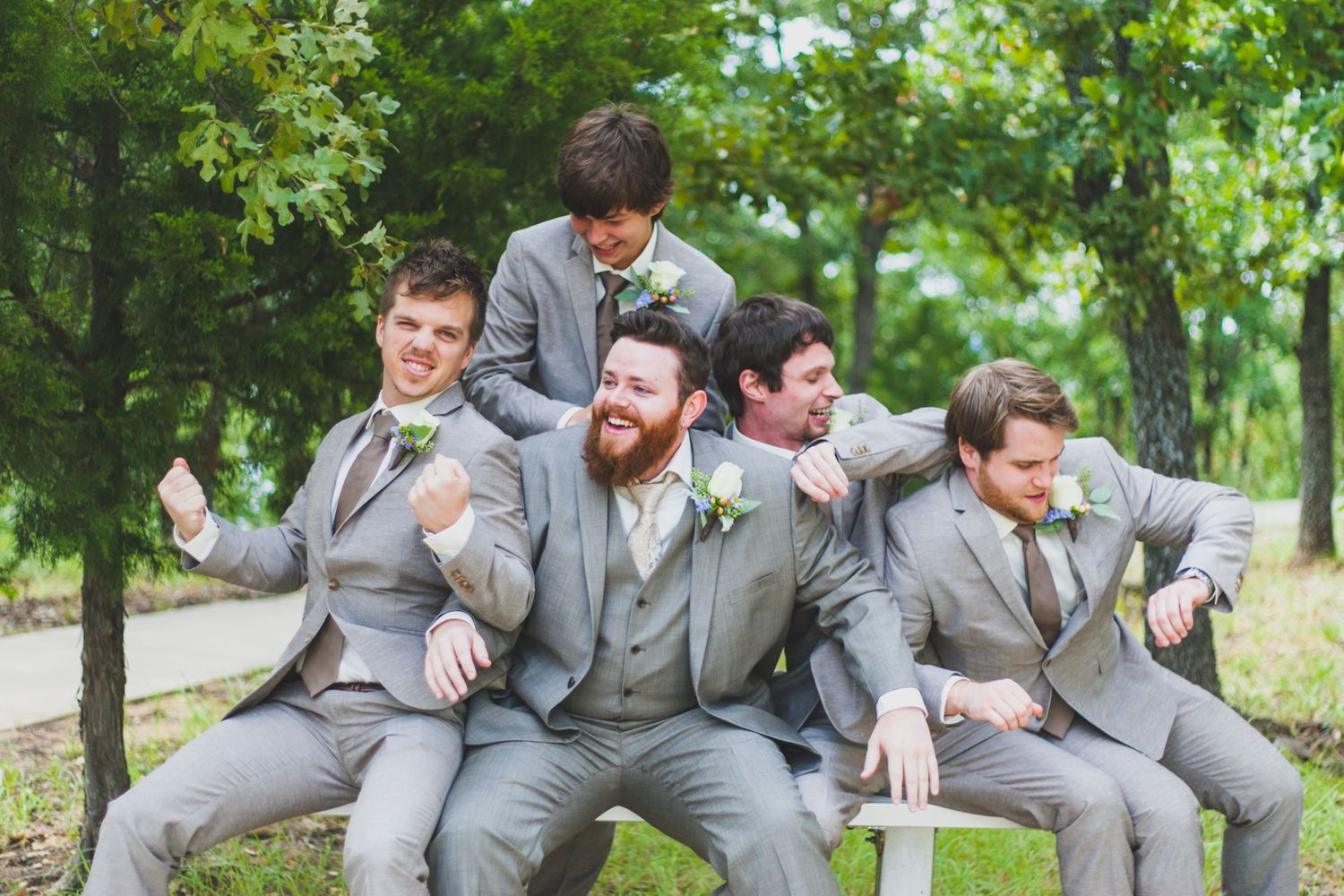Groomsmen in matching gray suits pose playfully outdoors for wedding photos. Denison North Texas Wedding Photography