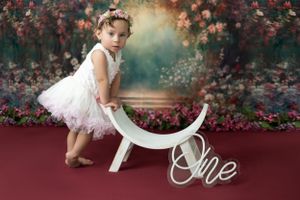 Milestone photoshoot featuring a child taking their first steps captured in a bright, cheerful studio.
