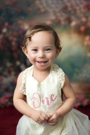 Milestone photoshoot featuring a child taking their first steps captured in a bright, cheerful studio.