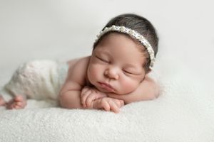“Newborn baby sleeping peacefully in a soft blanket during a studio session.”