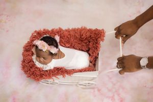 Beautiful posed newborn with parents, capturing the love and connection on a cozy backdrop.