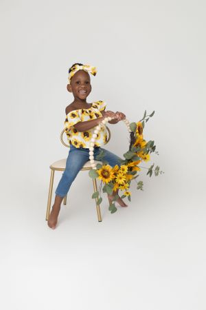 Playful portrait of a smiling child playing with a sunflower prop during a studio session in Bloomfield