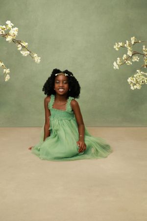 shot of a little girl smiling  cozy backdrop flower props  during a photo session.”