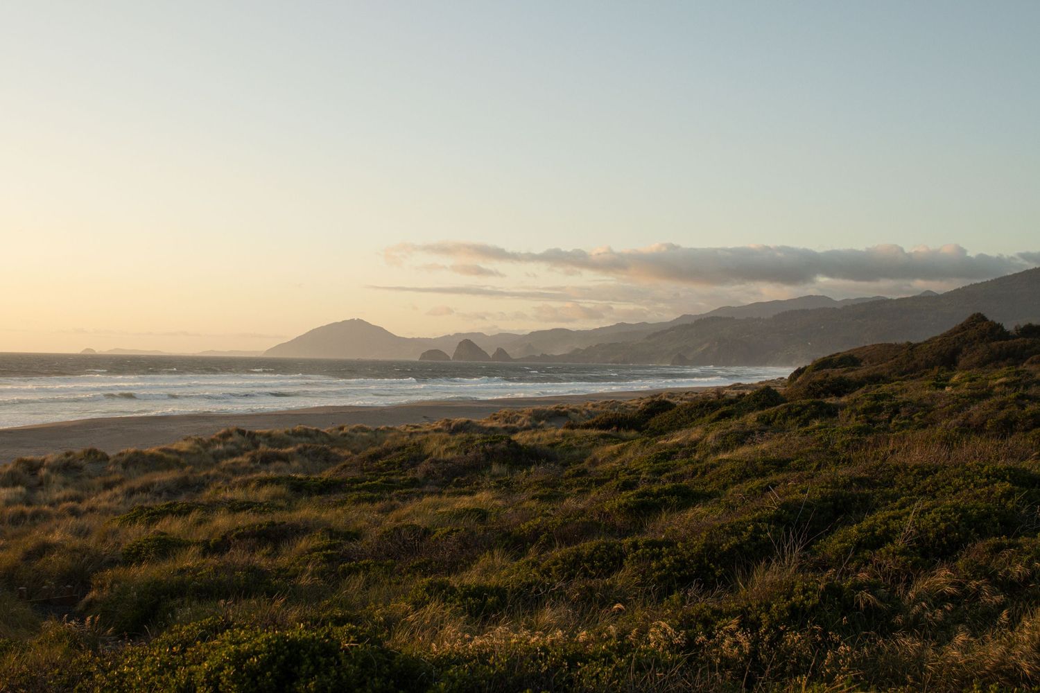 Cora Emilie Media -Panoramic sunset landscape of rolling hills and mountains against a dusky sky.