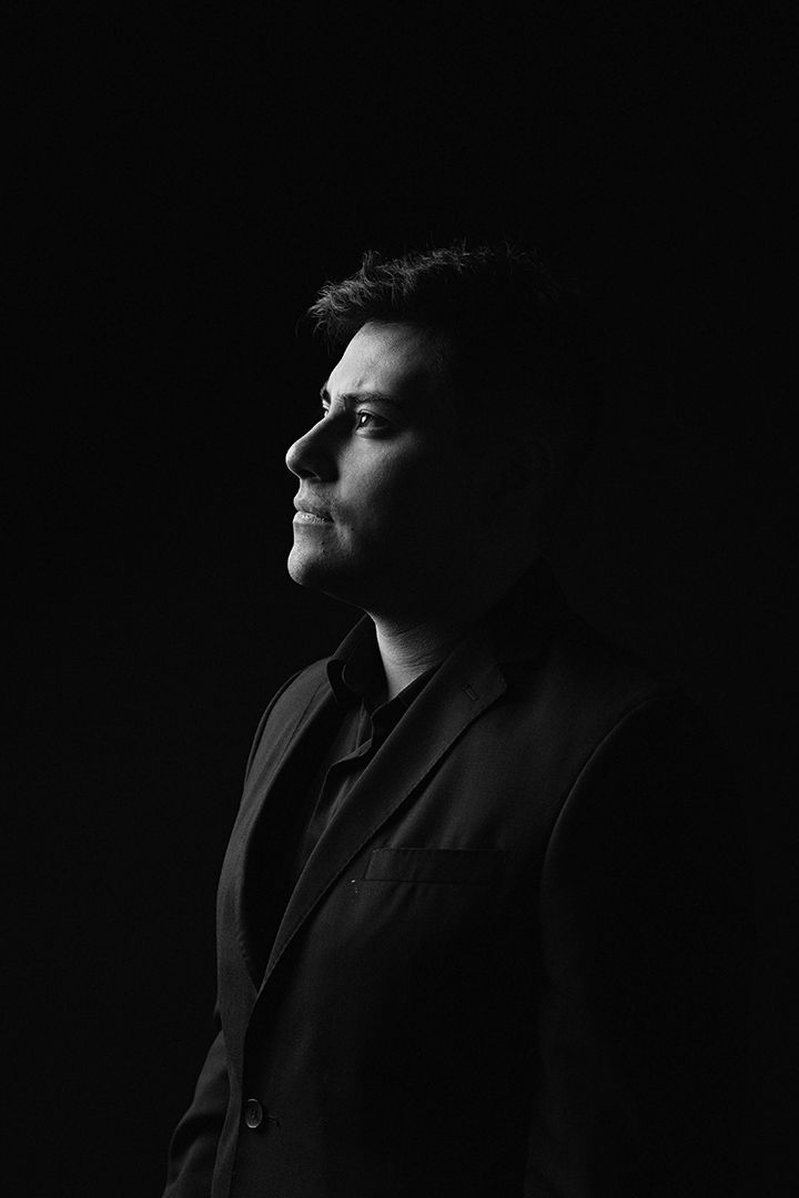 Dramatic black and white profile portrait with moody lighting against dark background.