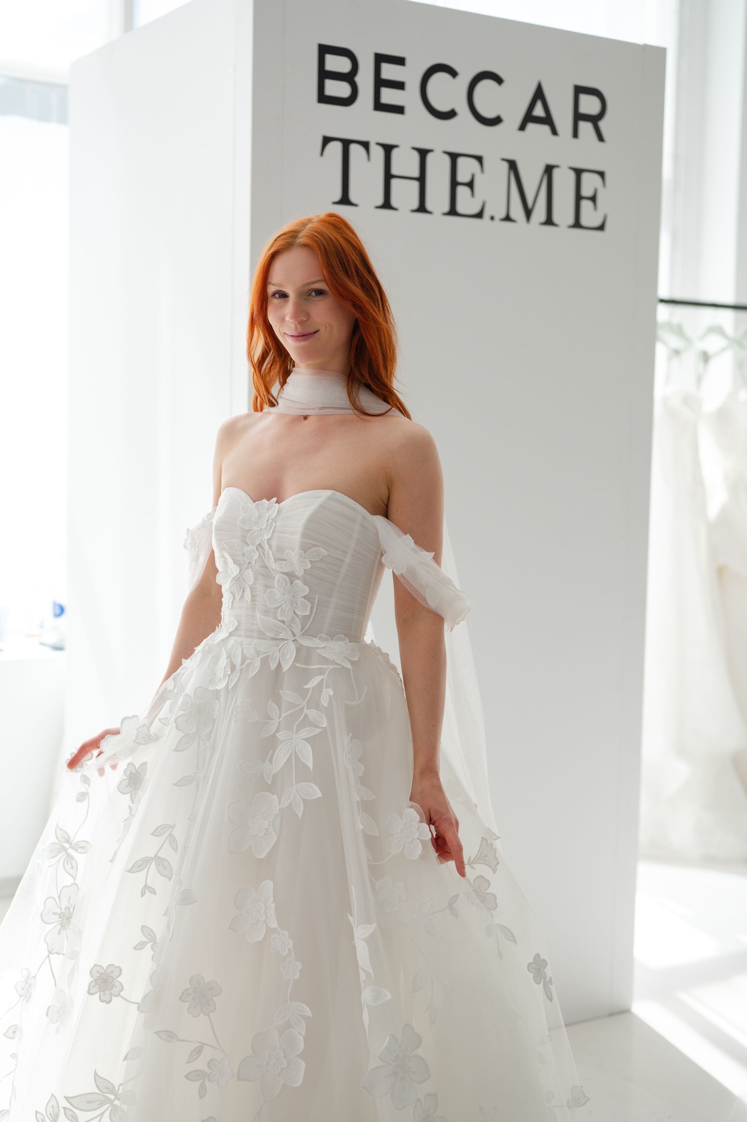 A white off-shoulder wedding gown with floral appliques is displayed at the Beccar Theme bridal boutique.
