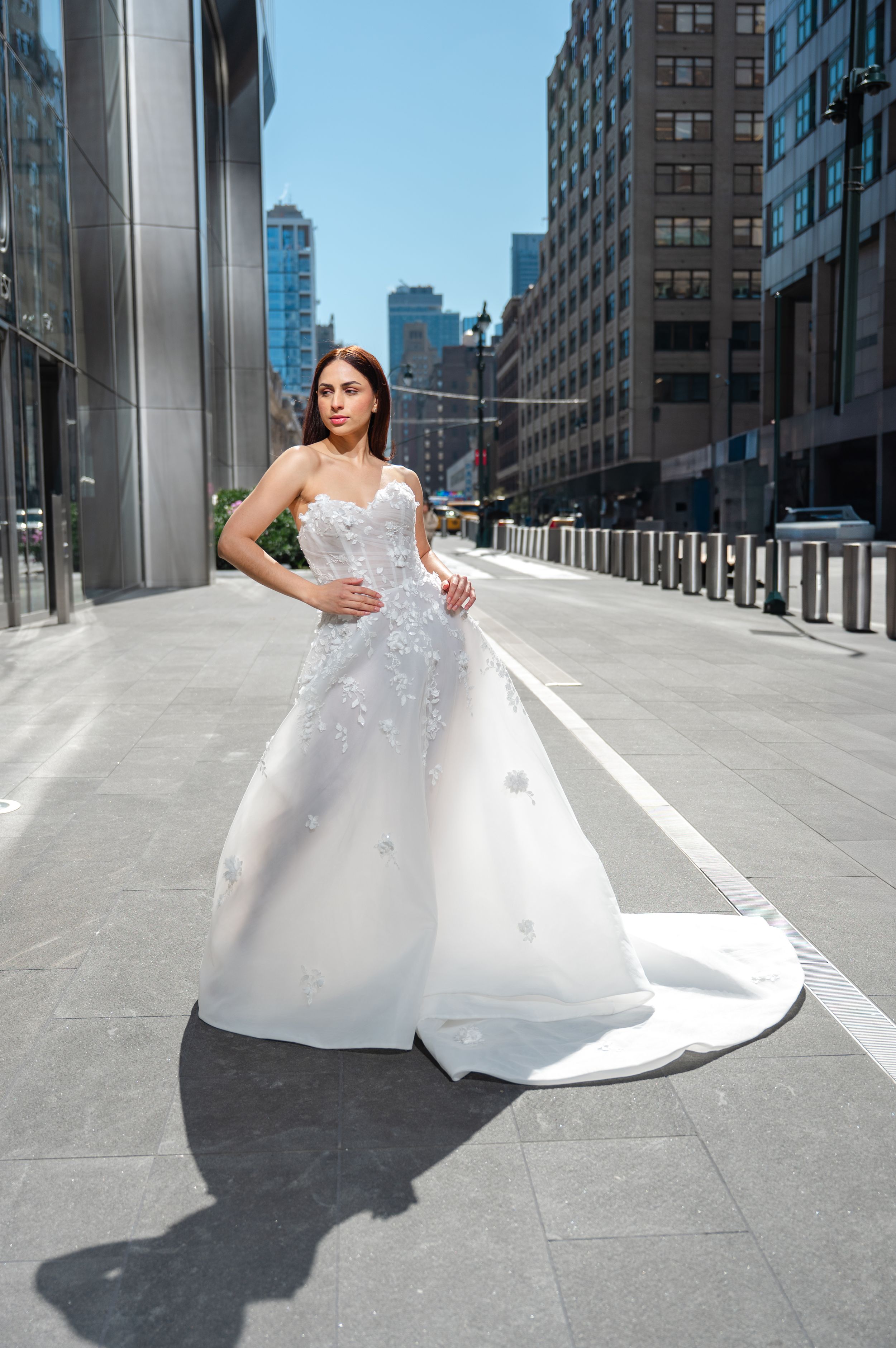 Stunning white bridal gown with sparkling details photographed against modern urban cityscape in downtown setting.