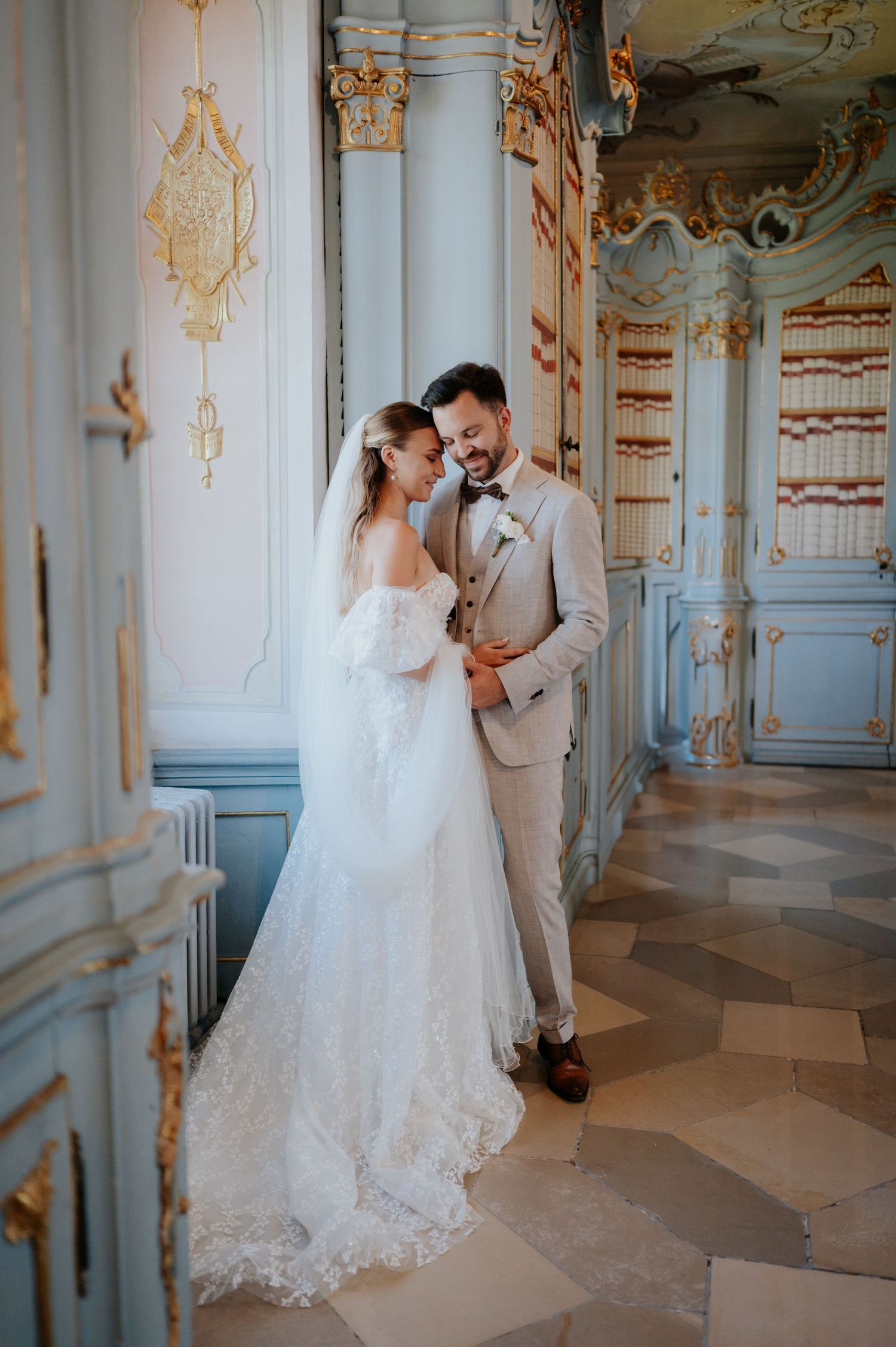 Ein romantischer Hochzeitsmoment, eingefangen in einem prunkvollen Barockpalast mit blau-goldener Ausstattung und Fliesenböden.