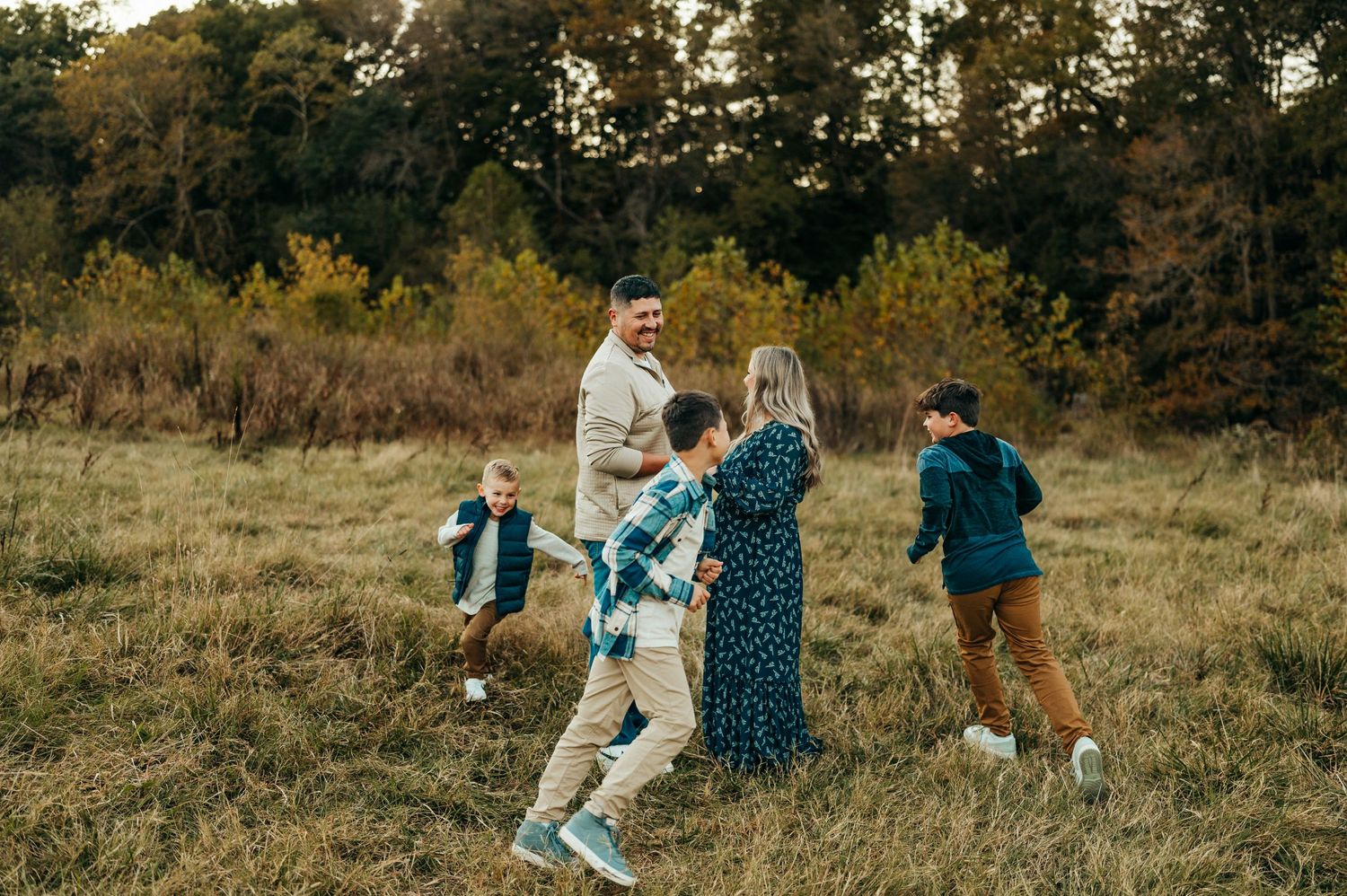 A playful family photo session in a fall field with casual coordinated outfits.