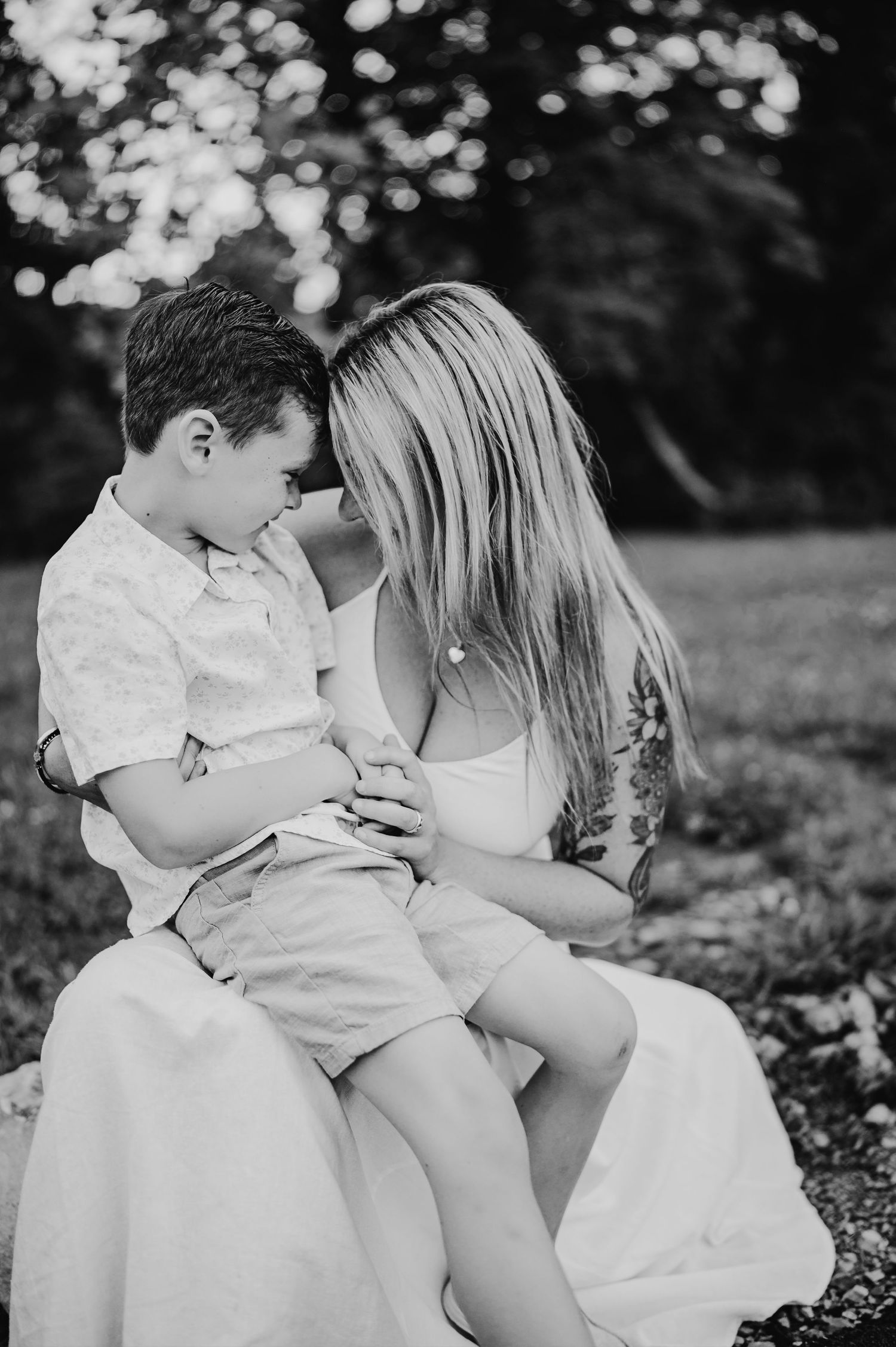 Black and white portrait of tender moment between mother and child outdoors.