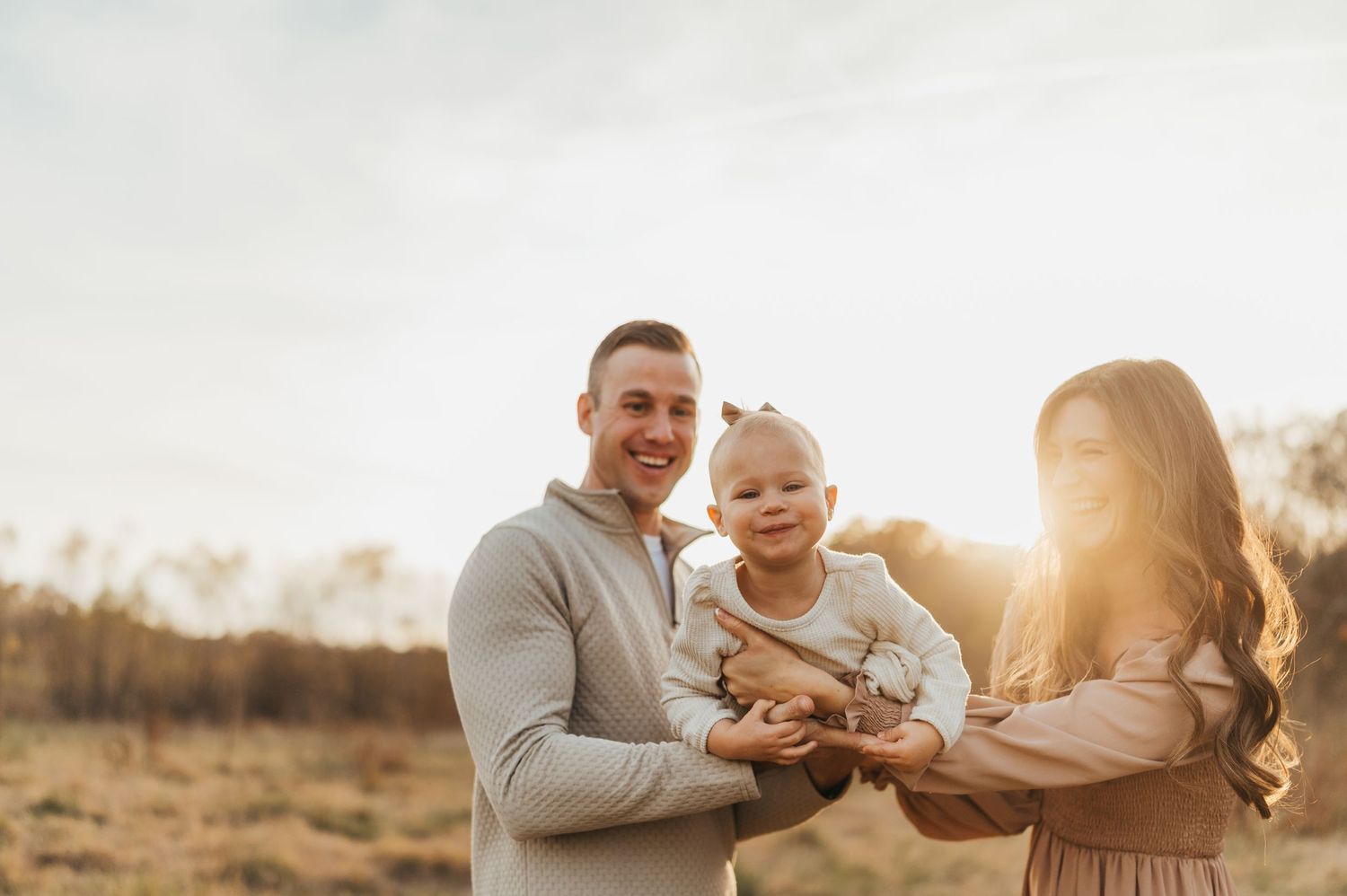 Family enjoying golden hour in a field with warm sunset lighting and casual attire.
