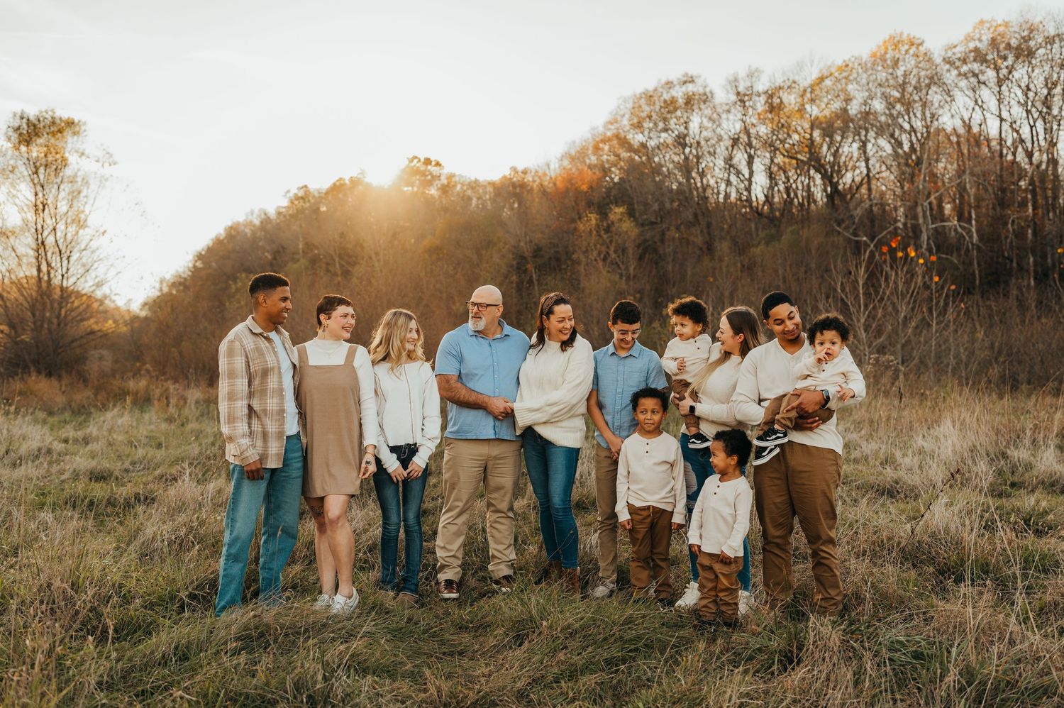 Extended family group portrait outdoors in casual clothes during golden hour.