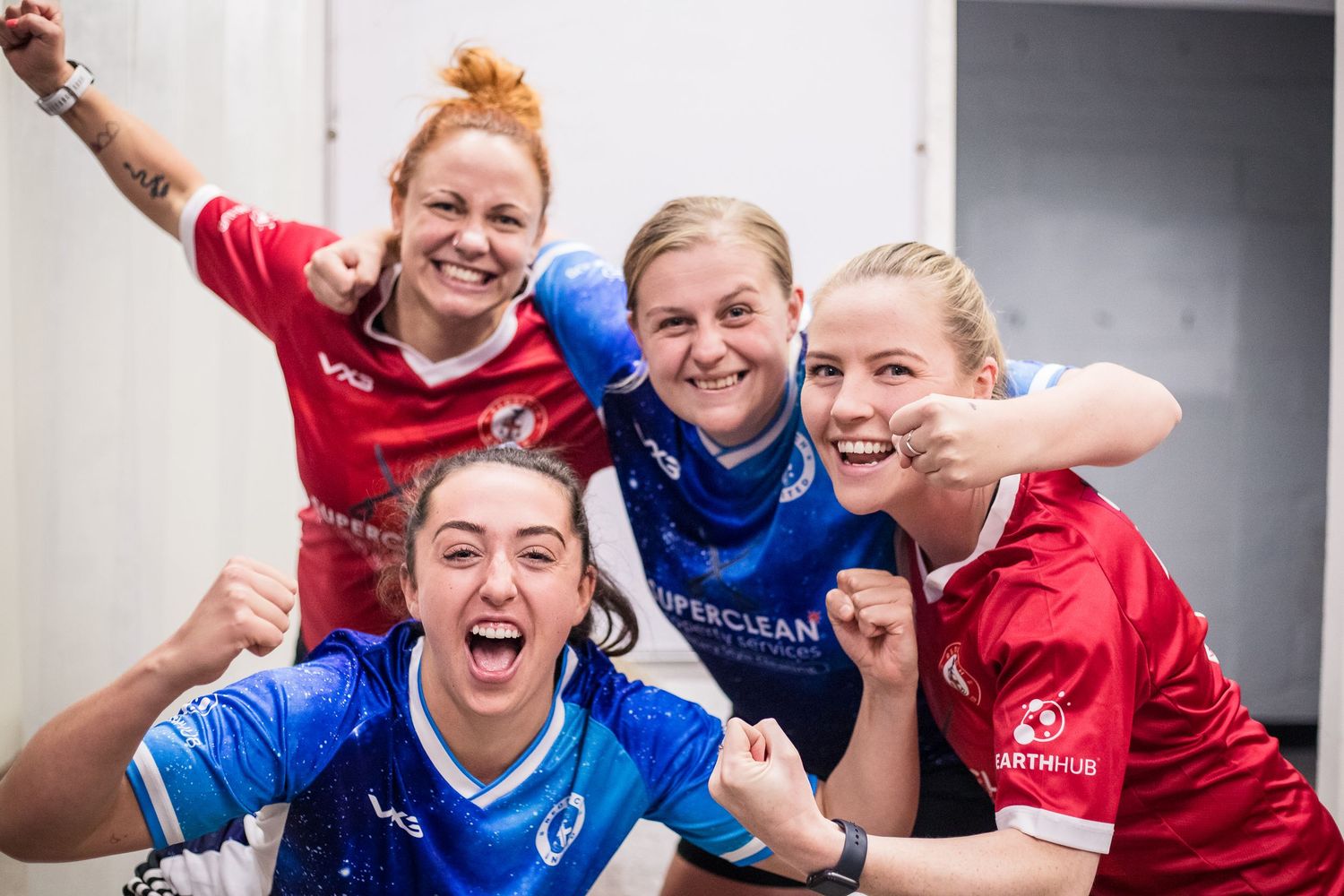 Women's football players celebrating together wearing both home and away shirts at Redditch Utd.