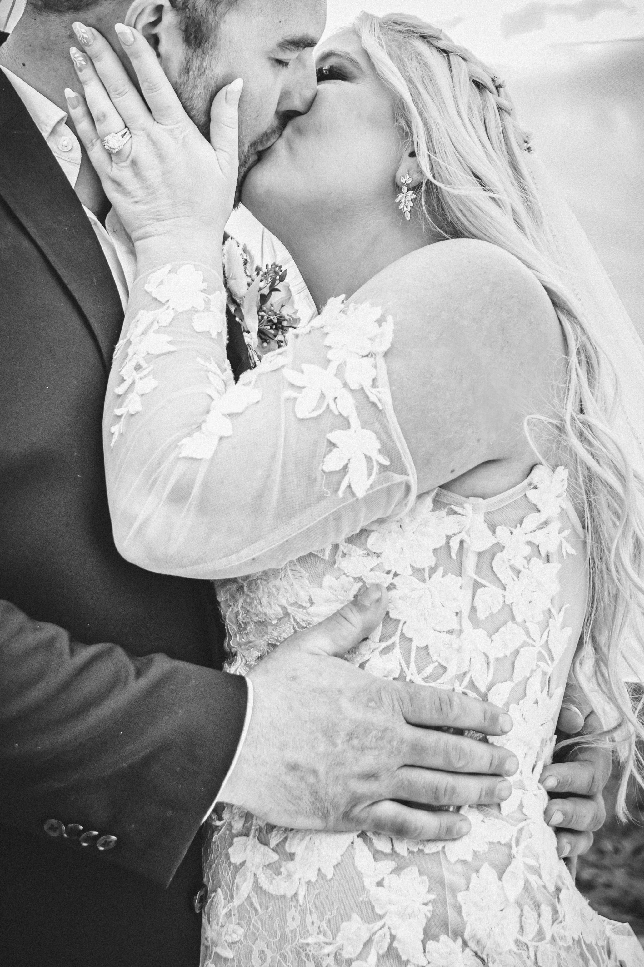 Black and white intimate portrait of bride and groom kissing on their wedding day.