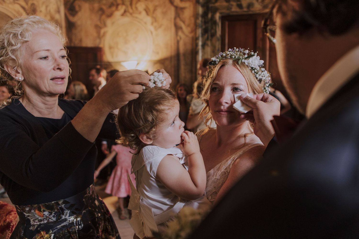 An intimate family moment during wedding celebrations in a beautifully decorated historic room.