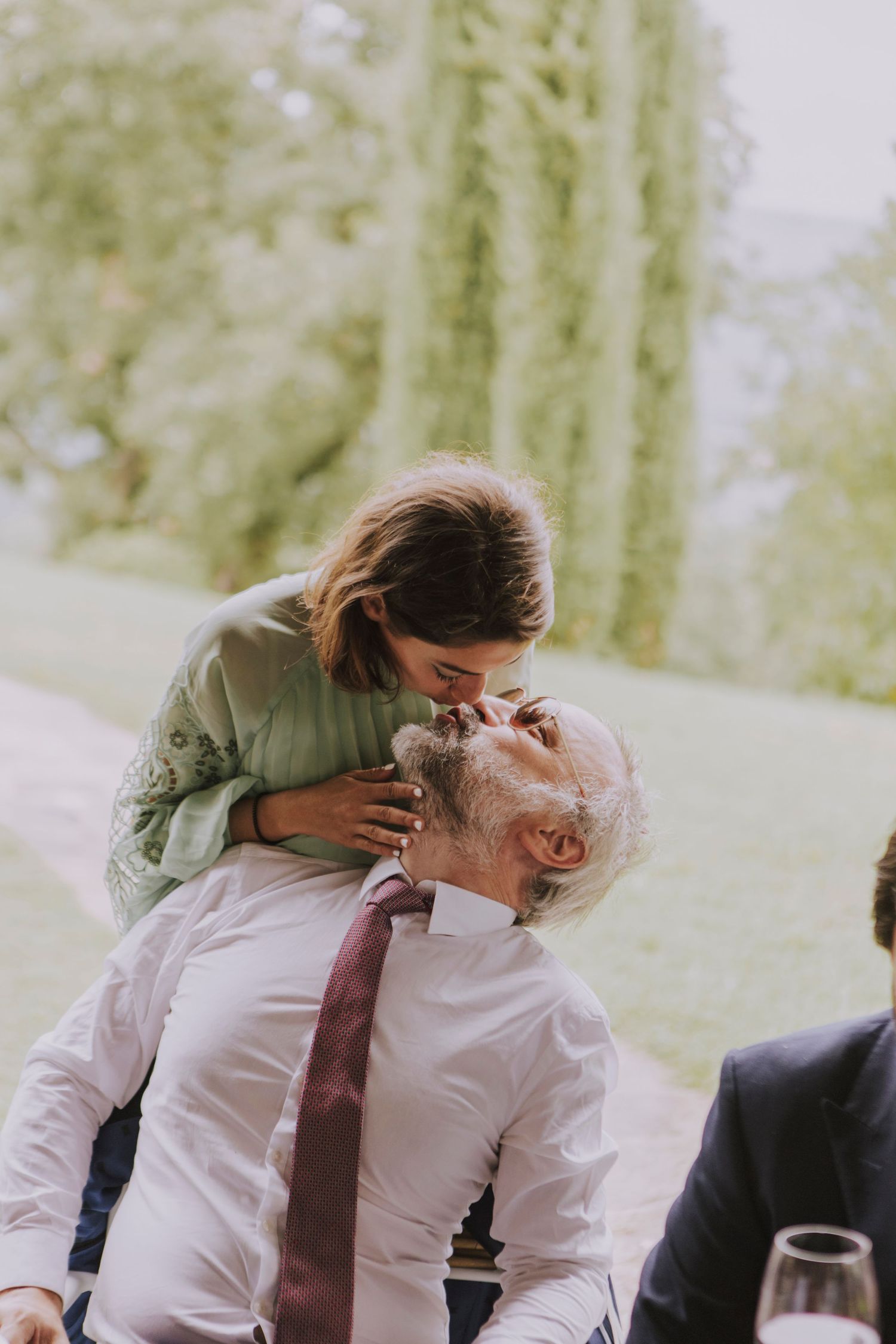 Two people share an intimate embrace during an outdoor wedding celebration.