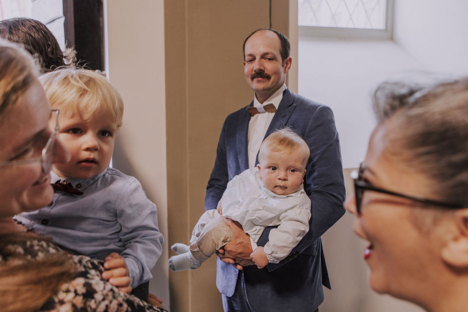 Candid indoor gathering with small children and guests at formal event.