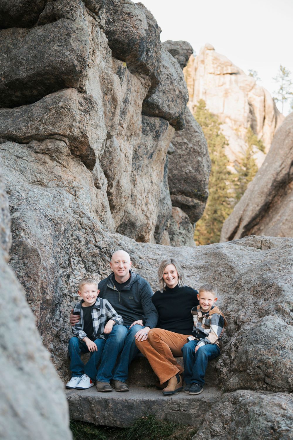 Group sitting together on large rocky formations in a natural outdoor setting.