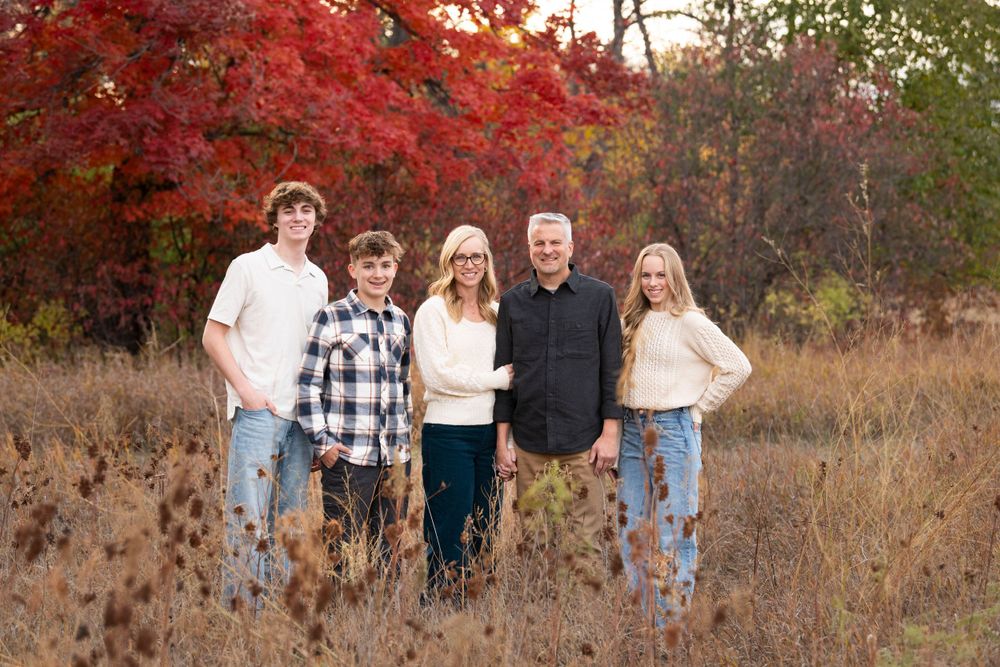 Casual group portrait in a natural setting with red fall colors and dried grass.
