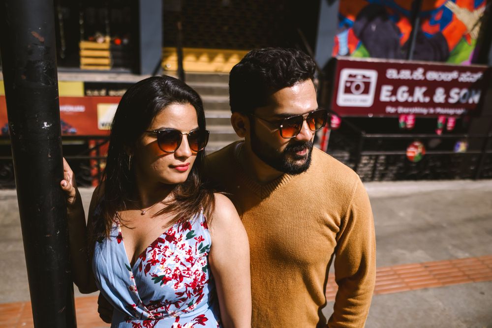 A couple enjoying a casual stroll through a bustling urban street with shops and storefronts.