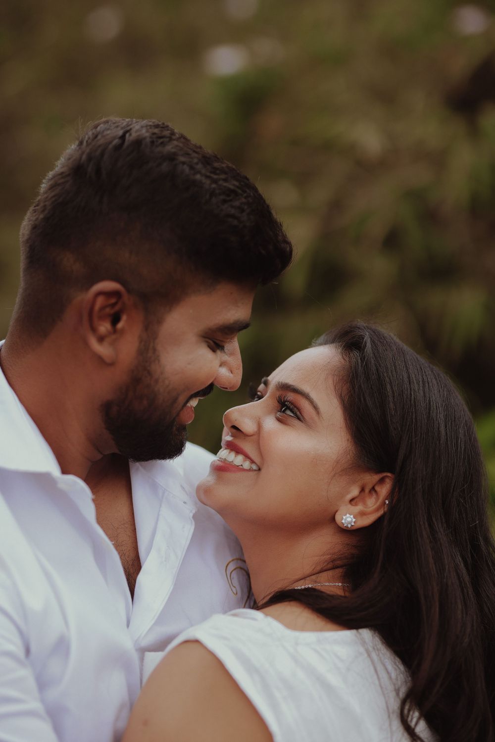 An intimate portrait of a couple in white attire sharing a tender moment.