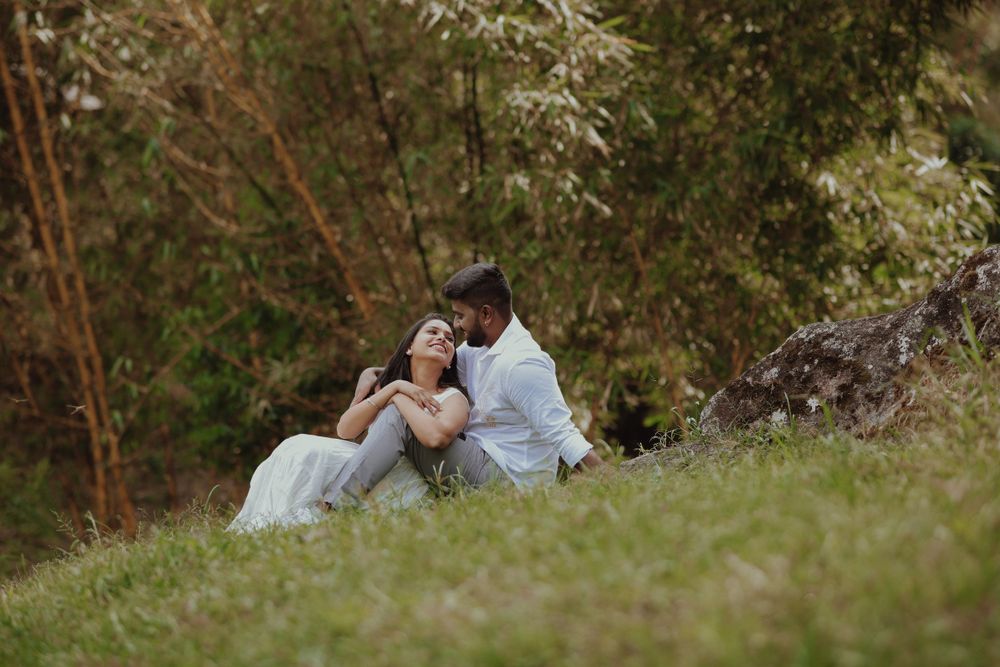 A romantic moment shared in a lush green natural setting with trees in the background.