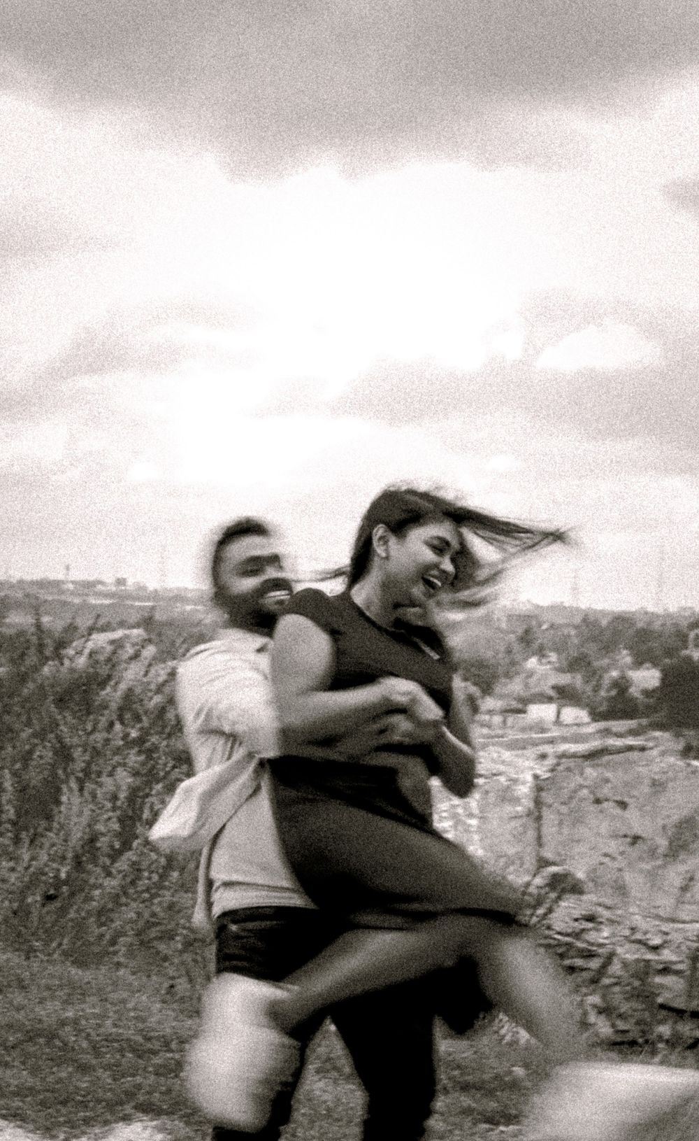 Playful black and white sequence of a couple dancing and spinning together in an outdoor setting.