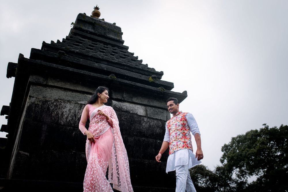 Couple in traditional attire posing in front of an ancient temple structure.