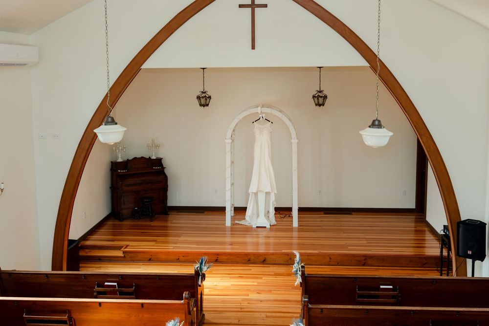 Interior of a traditional chapel with wooden arches and cross displayed at the altar.