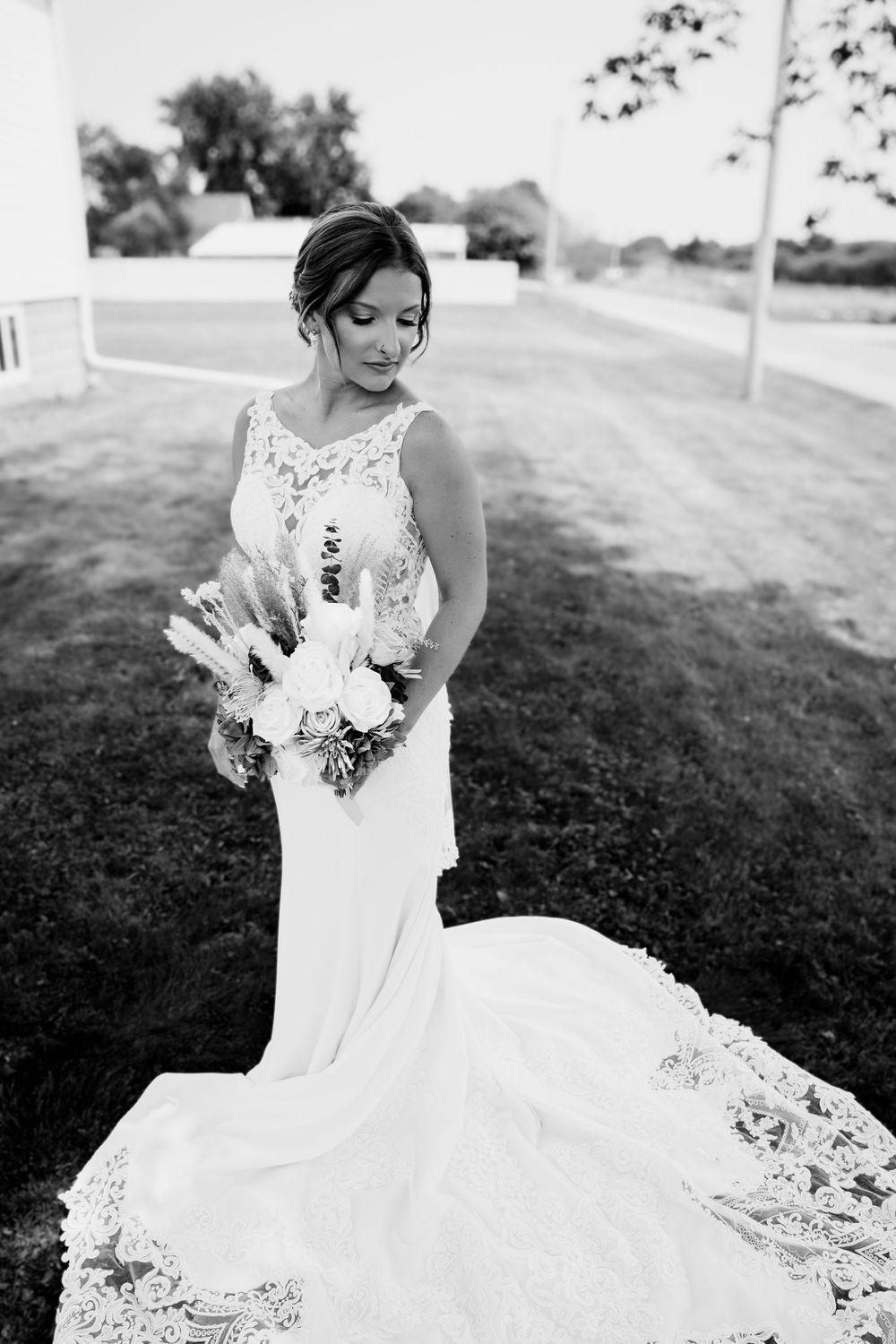 Close-up details of an elegant white lace wedding dress with floral bouquet.