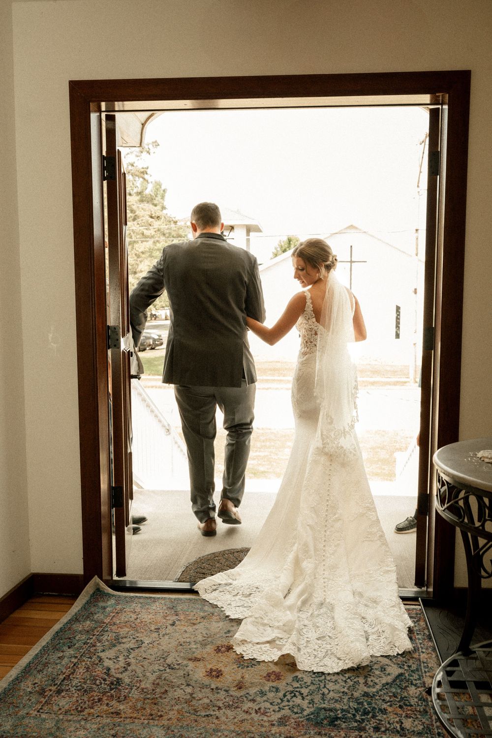 Silhouette of a wedding couple walking through doorway with dramatic backlighting.