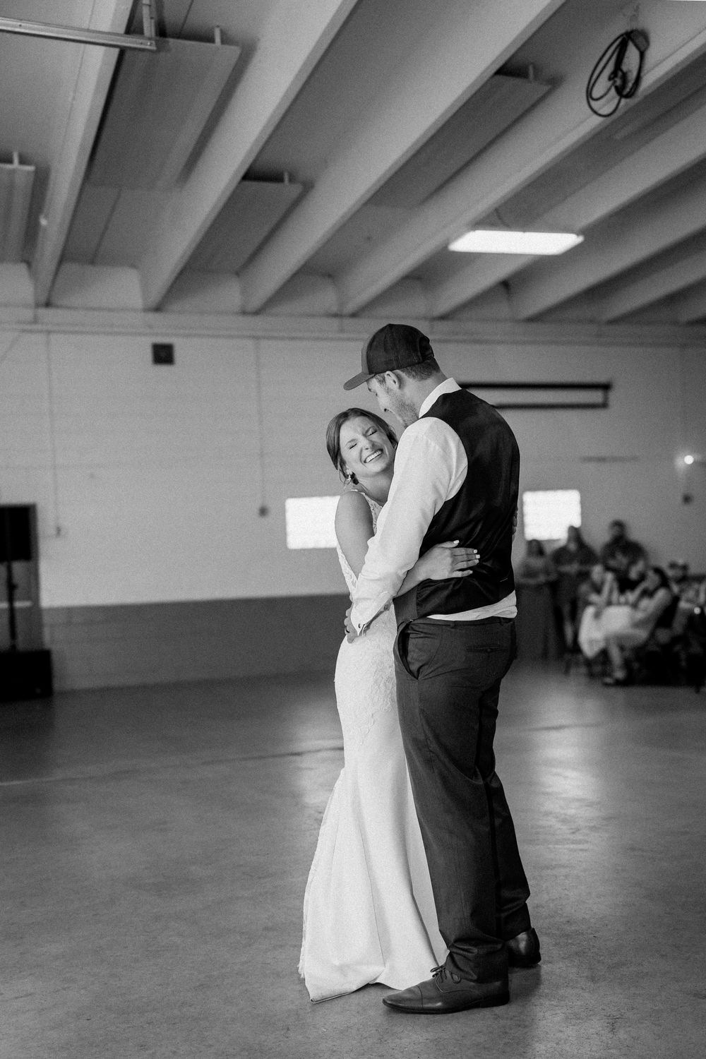 Black and white photo of a couple sharing an intimate dance moment in an empty hall.