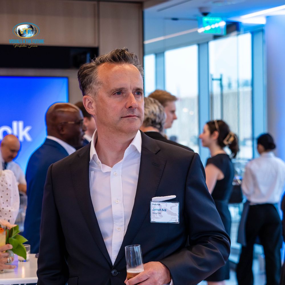 Business professionals networking at a corporate event with drinks in modern office space.
