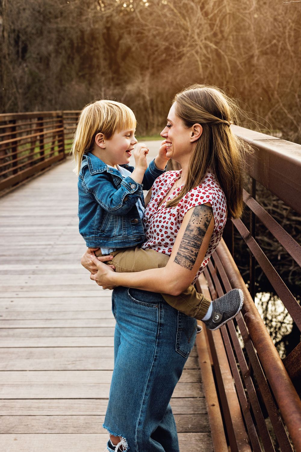 A touching moment between parent and child sharing affectionate laughter on a wooden bridge in warm autumn lighting.