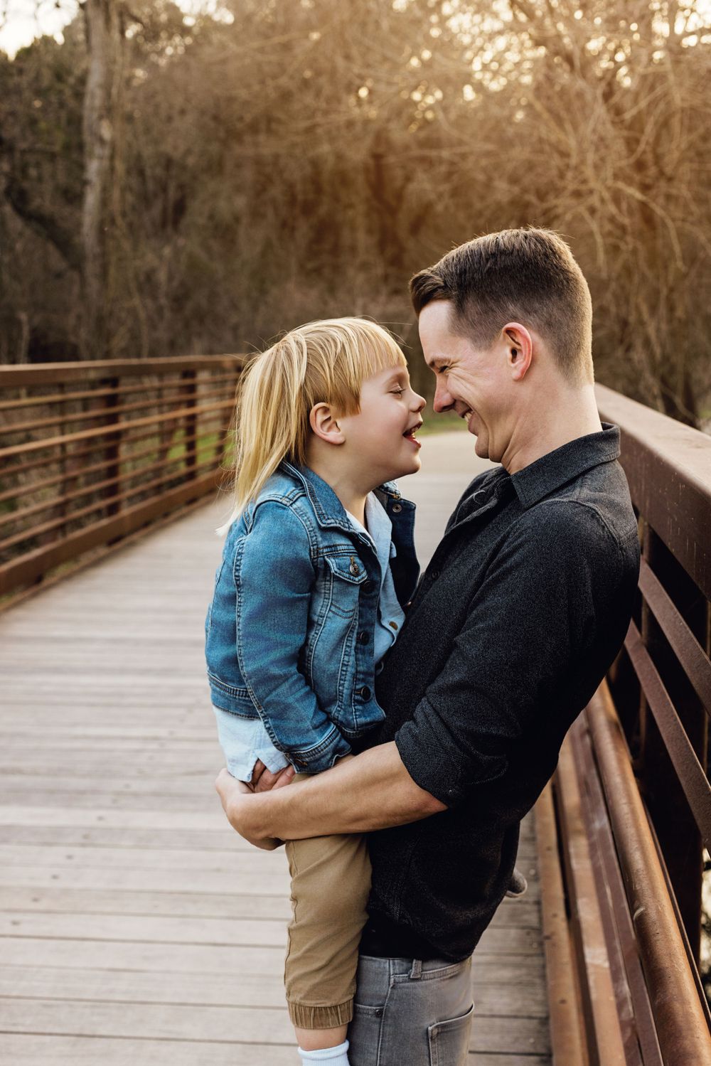 A tender moment between parent and child sharing laughter together on a wooden bridge at sunset.