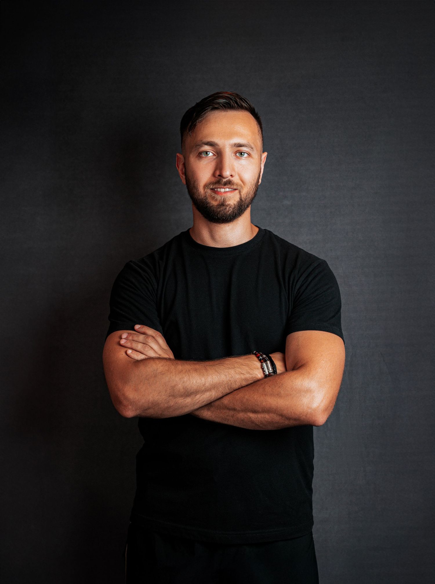 Professional studio portrait of someone in a black t-shirt against a dark background with dramatic lighting.