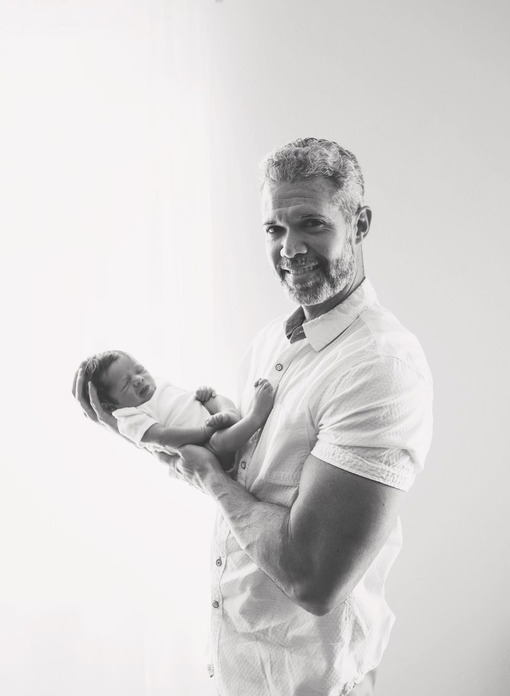 black and white newborn photography. father holding baby back-lit in Pensacola FL, Pensacola lifestyle newborn photography