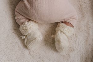 Newborn baby with handmade knitted booties. Feet of newborn baby.