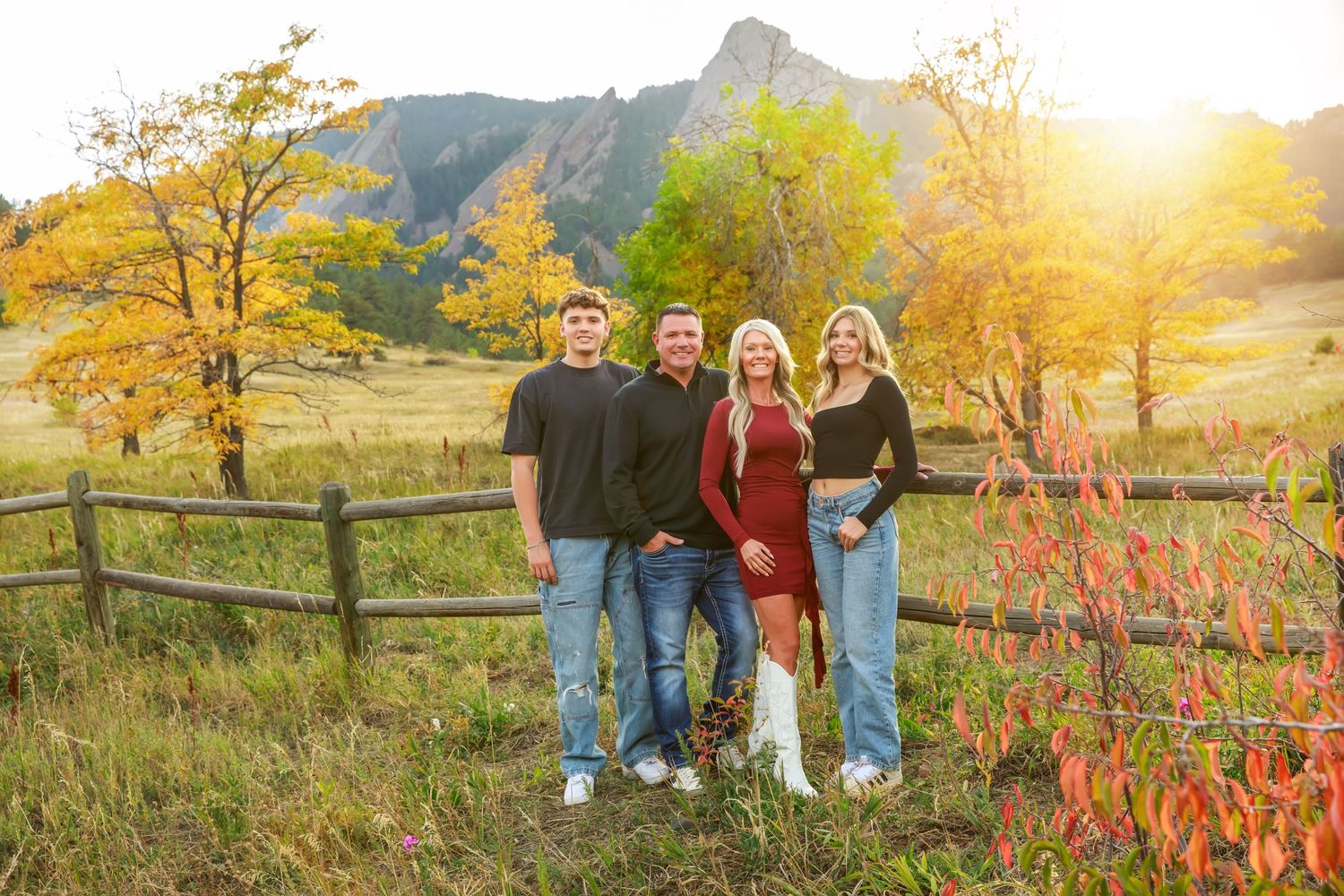 Family portrait in casual attire against mountain landscape at golden hour.