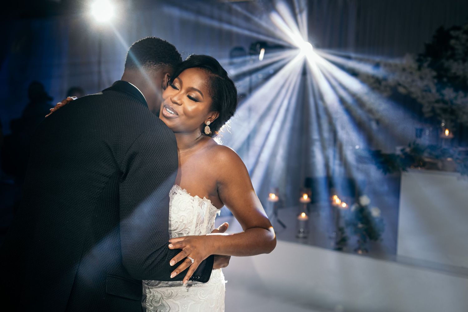A couple shares their first dance under dramatic spotlights at their wedding reception.