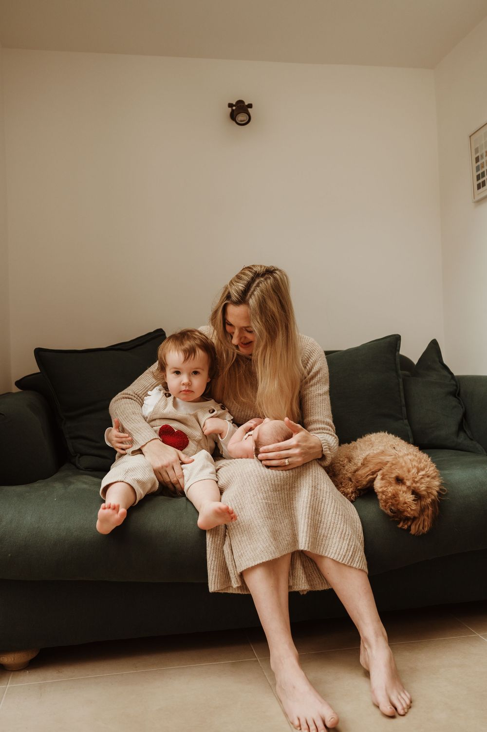 A family moment on a dark green couch with a fluffy dog resting nearby.