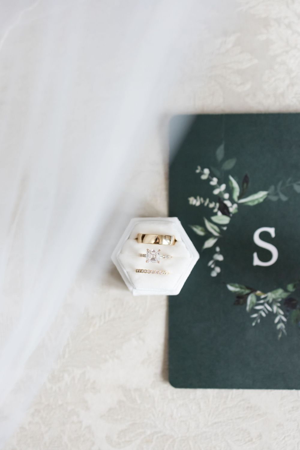 Three close-up views of silver engagement rings with diamonds displayed on a dark green card against white surfaces.